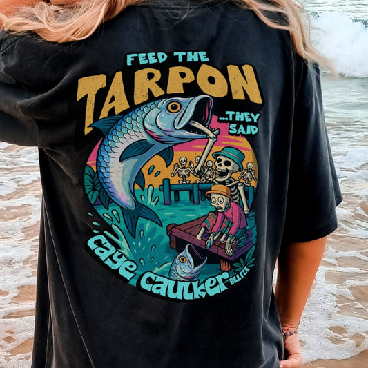 Person wearing a black t-shirt with a colorful graphic of skeletons and tarpon on the beach in Caye Caulker, Belize